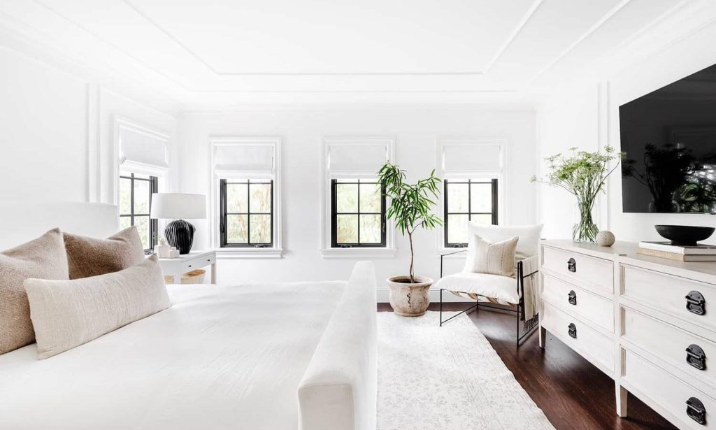 Kamar tidur all white dengan elemen hitam pada bingkai jendela dan aksen dekoratif, menciptakan desain monokrom elegan.